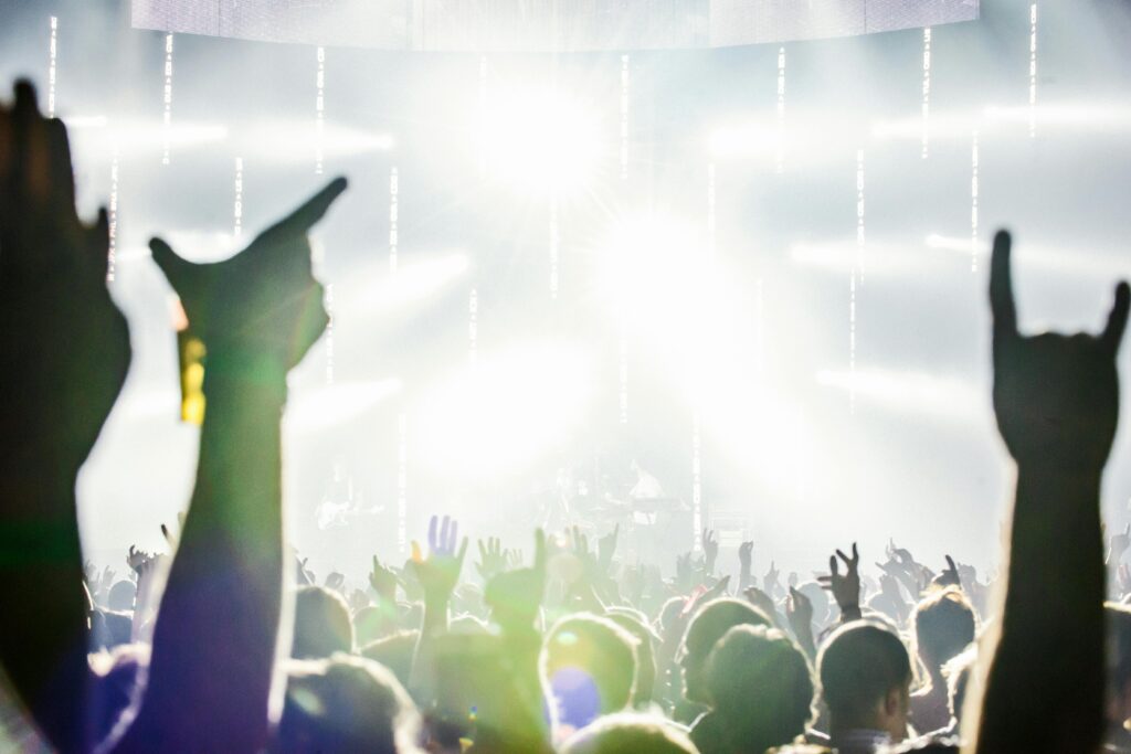 Dynamic crowd at a live concert with hands raised, celebrating music and energy.